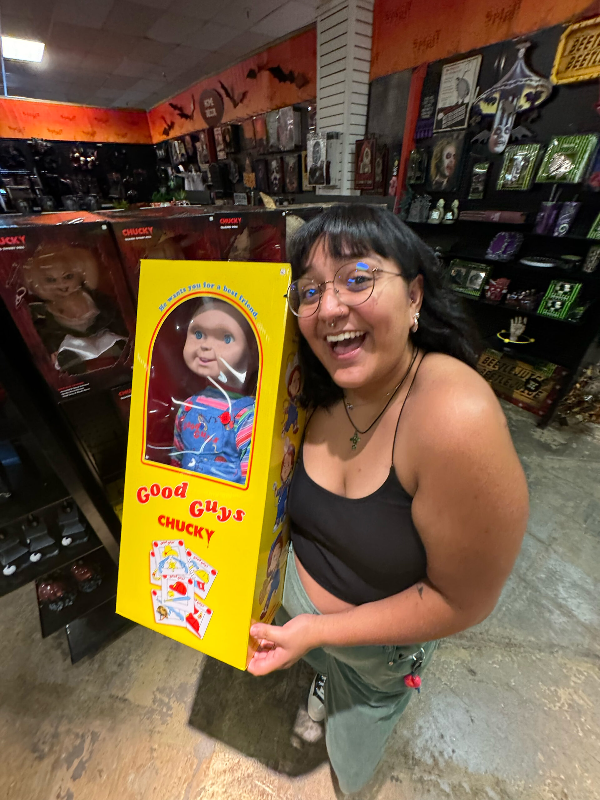 a woman holding a packaged Chucky doll.