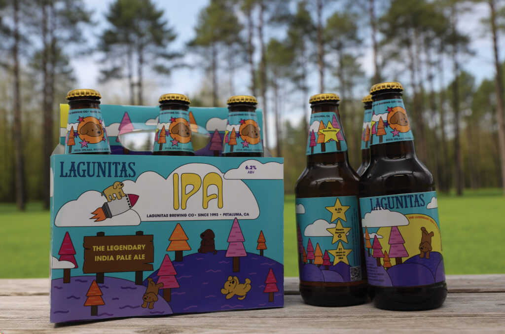 Lagunitas IPA case & bottles outdoors on a wooden table.