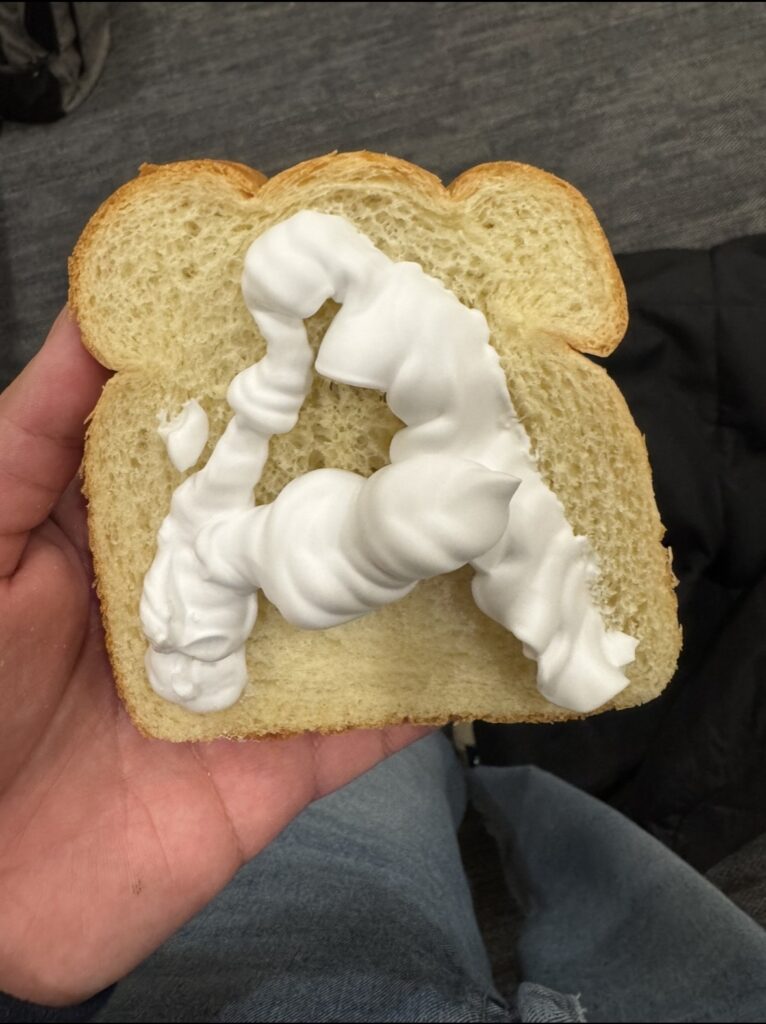 a slice of bread with shaving cream on it in the shape of the letter 'A'.